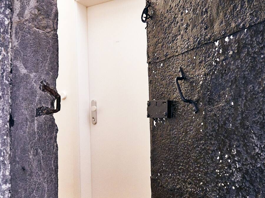 A door with a metal latch and a textured wall with a metal fixture.