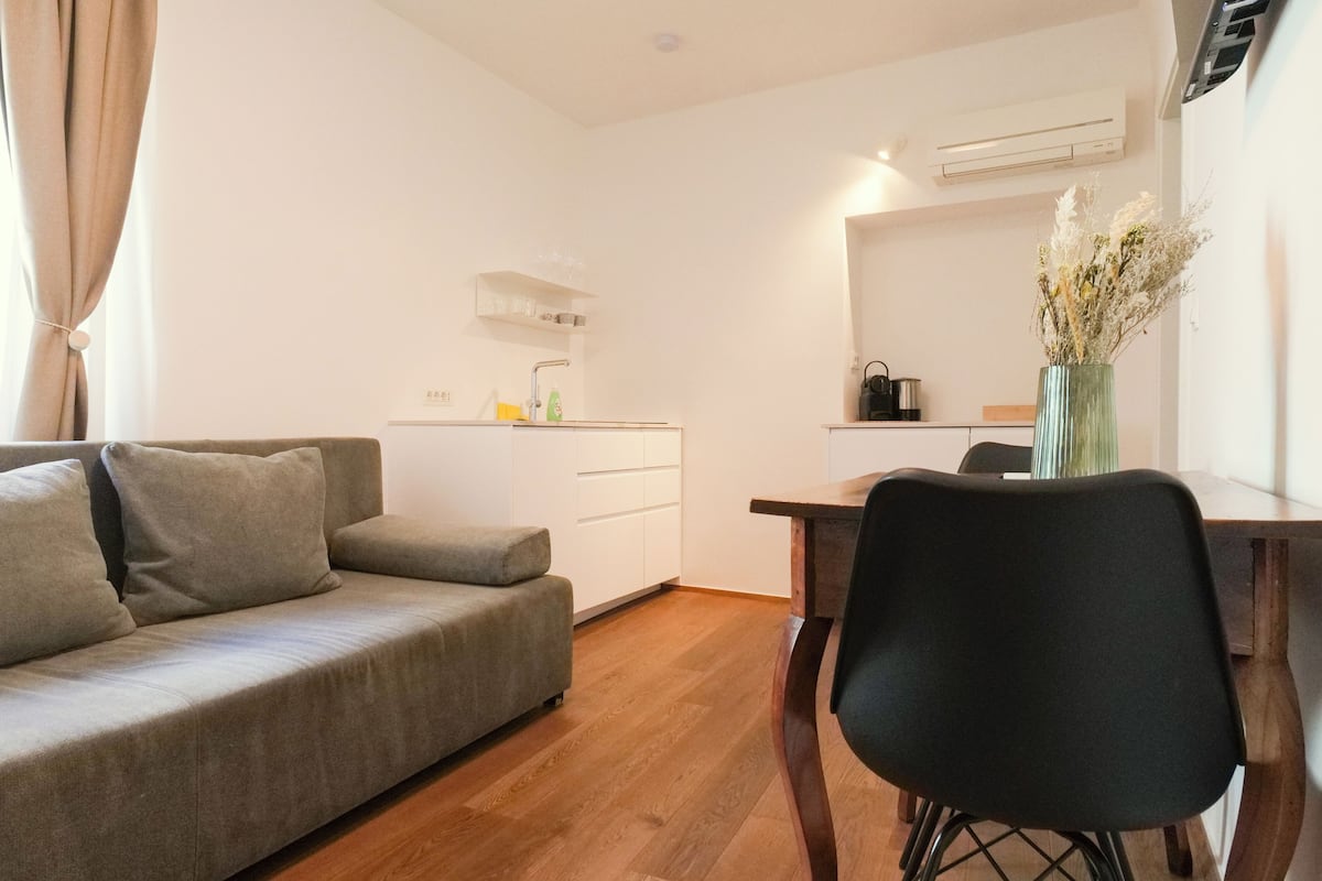 Un espacio habitable pequeño con sofá, una mesa de comedor y una silla.