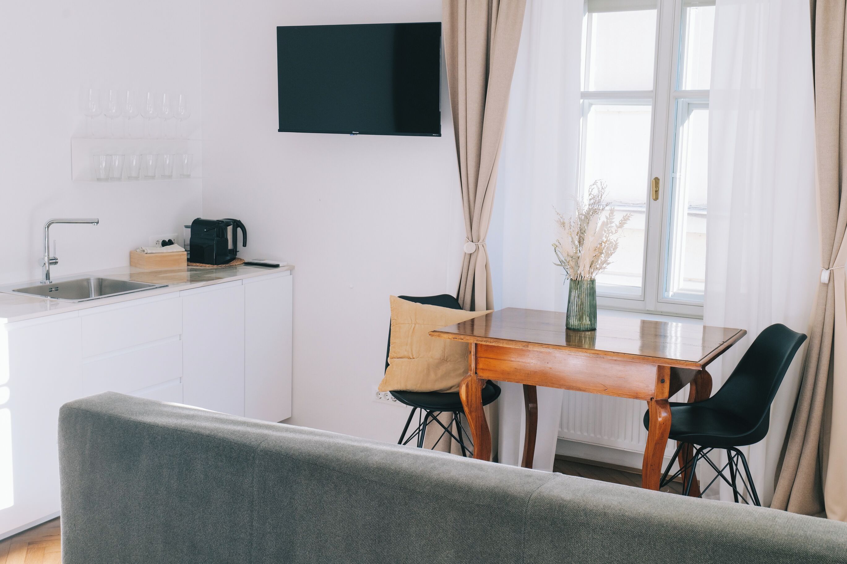 A modern kitchen with a flat-screen TV, a coffee maker, and a dining area with a wooden table and chairs.
