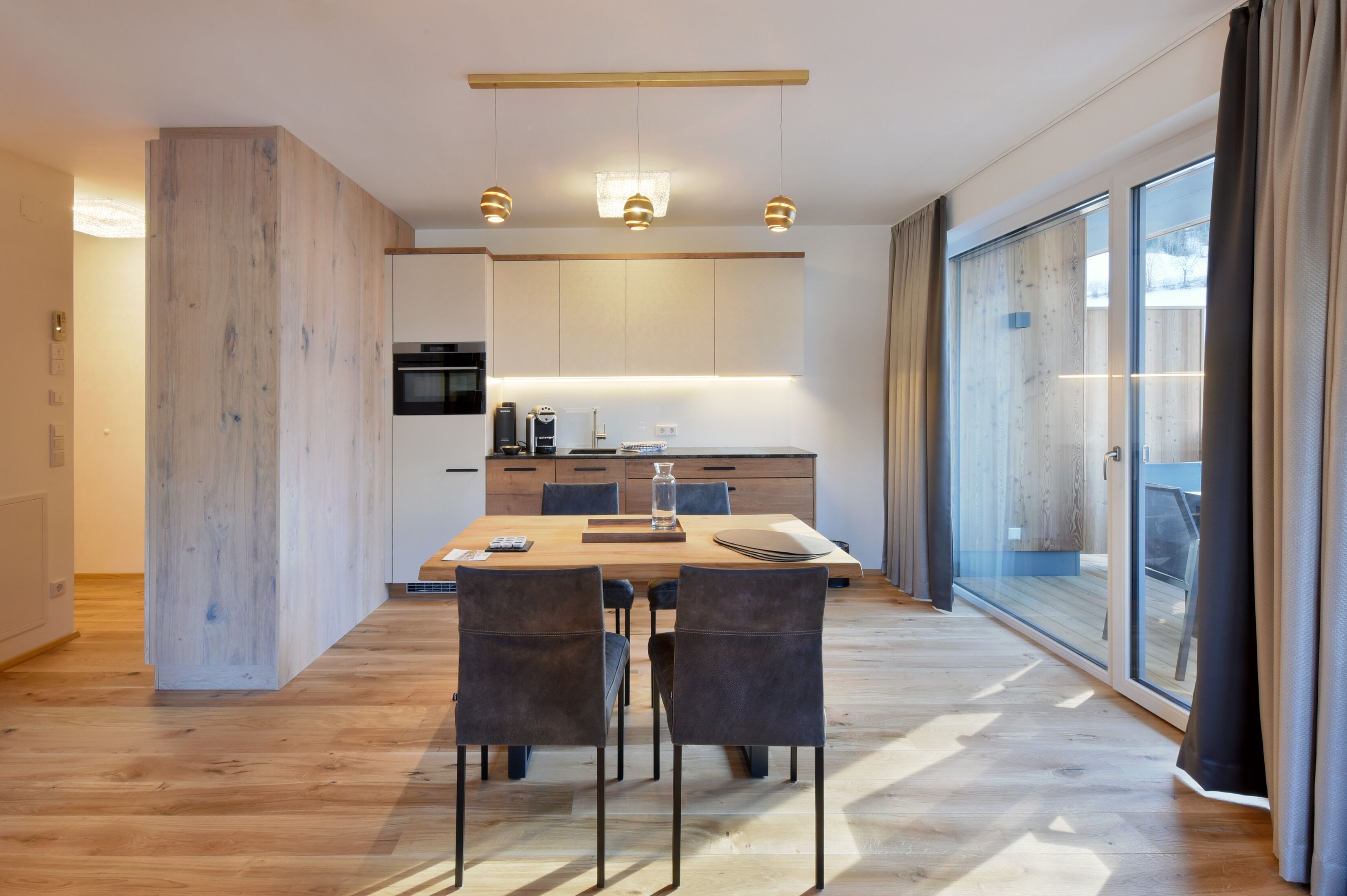 A modern kitchen with a dining area, large windows, and a sliding glass door.