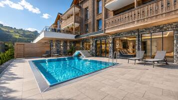Una piscina al aire libre, sombrillas, sillones reclinables de piscina
