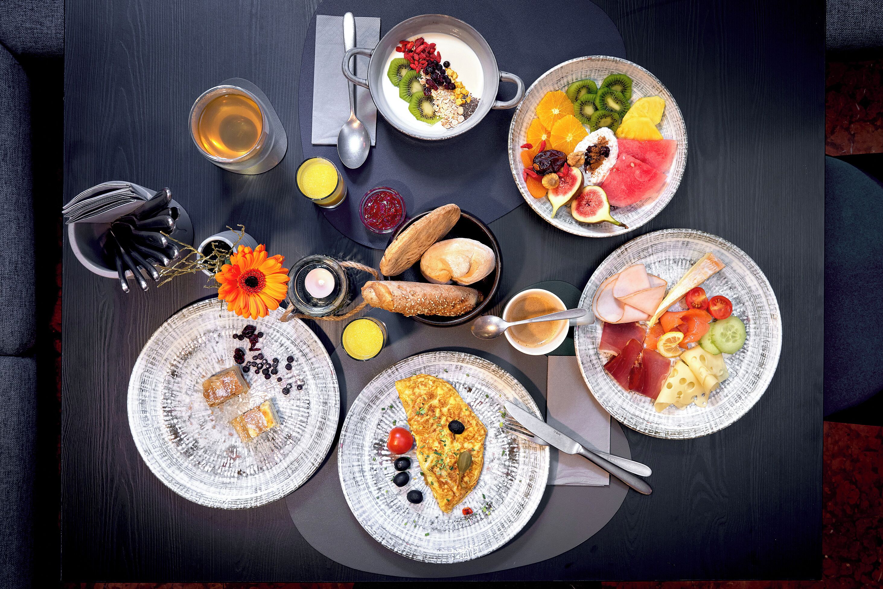 A breakfast table with various food items, a cup of tea, and a plate with a flower.