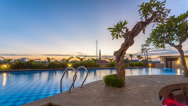 Piscina con vista a una torre distante, rodeada de follaje y un cielo despejado.