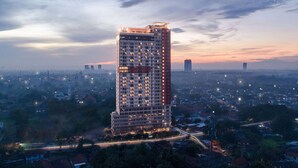 Un edificio alto con varios pisos, rodeado por un paisaje urbano al anochecer.