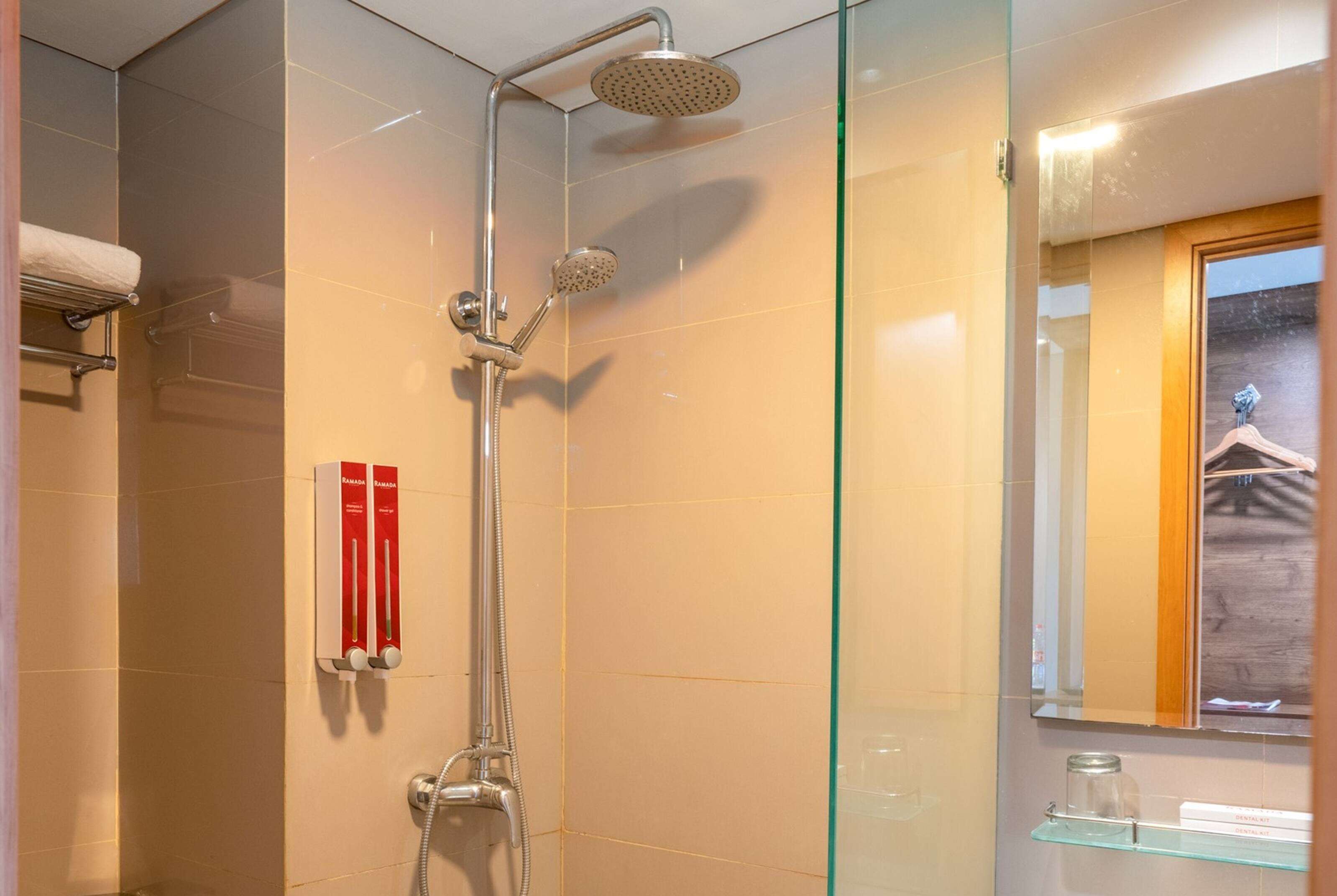 A modern bathroom with a glass shower enclosure, a towel rack, and a glass shelf with toiletries.