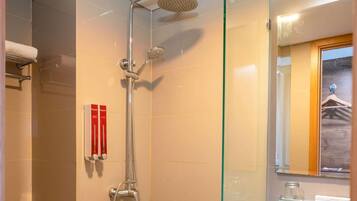 A modern bathroom with a glass shower enclosure, a towel rack, and a glass shelf with toiletries.