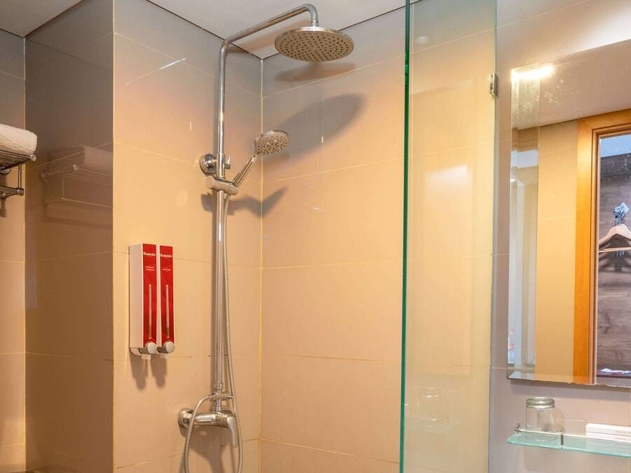 A modern bathroom with a glass shower enclosure, a towel rack, and a glass shelf with toiletries.