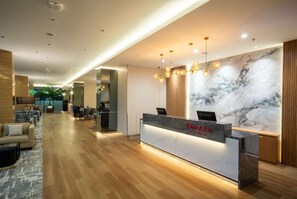 A modern reception area with a marble wall, wooden flooring, and a reception desk. - Ramada by Wyndham Serpong (South Tangerang)
