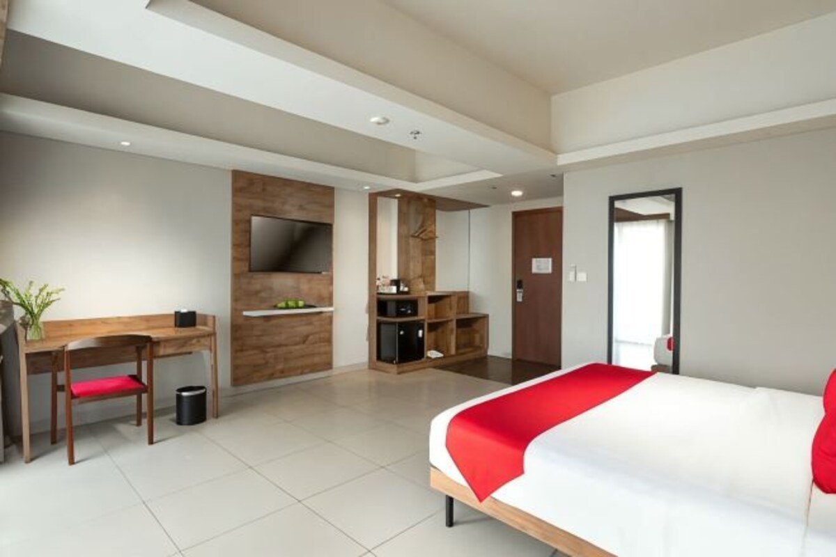 A modern hotel room with a bed, desk, and seating area.