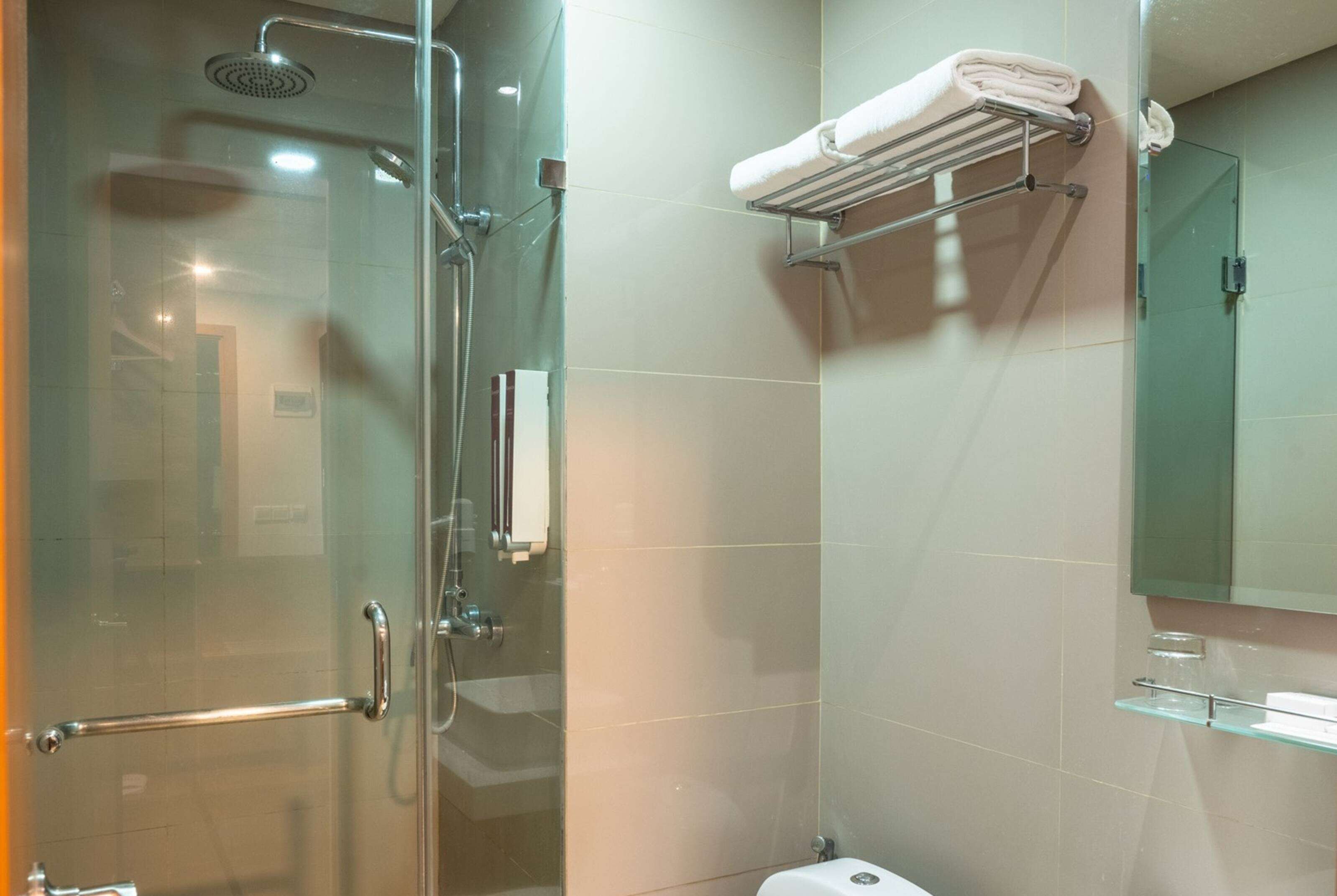 Un baño moderno con cabina de ducha de vidrio, lavamanos de vidrio y un perchero para toallas.