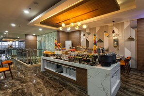 A modern hotel lobby with a marble floor, a buffet area with various food options, and a seating area with chairs. - Ramada by Wyndham Serpong (South Tangerang)
