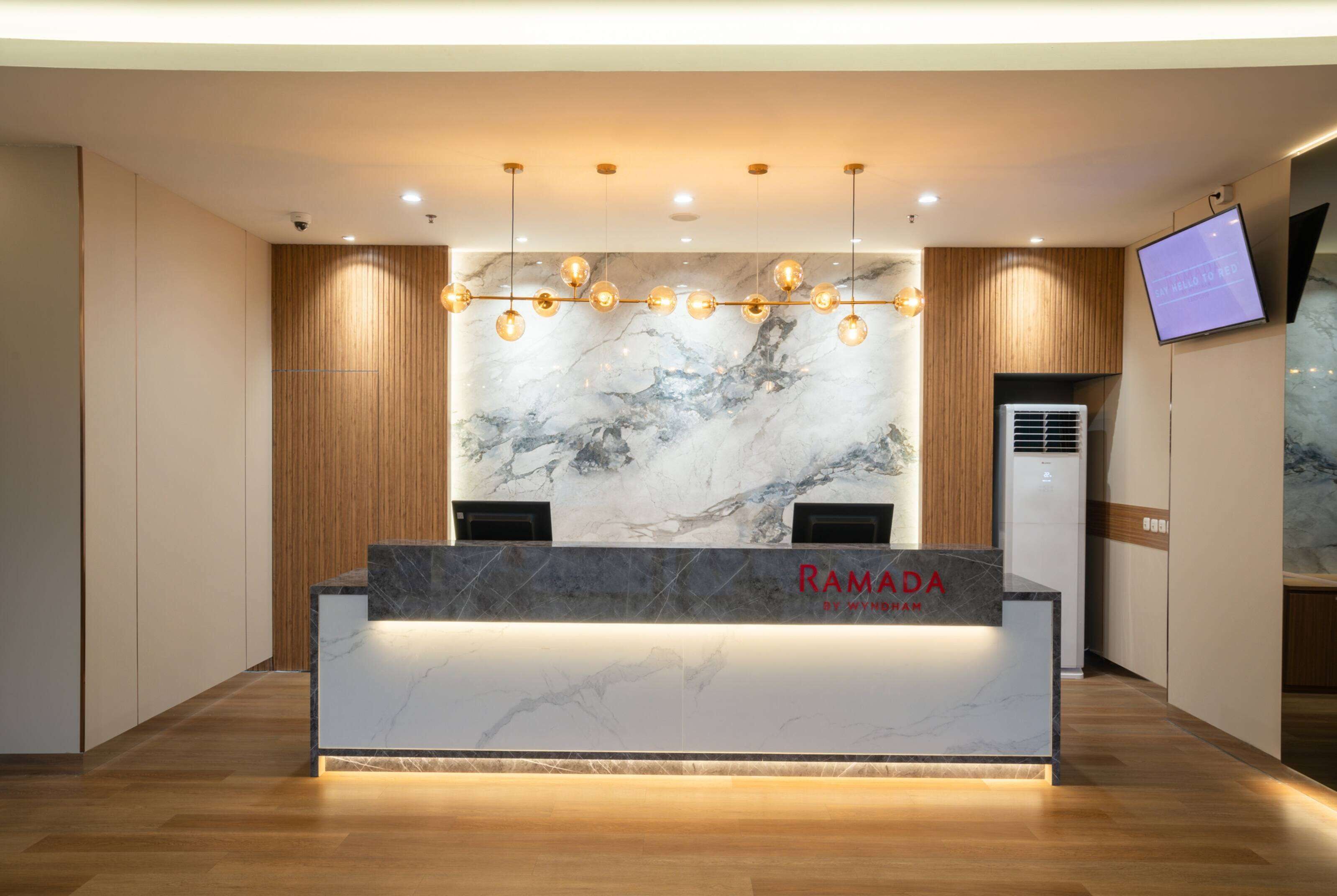A reception desk with a marble top, wooden paneling, and a mounted television.