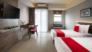 Habitación de hotel con dos camas, un televisor de pantalla plana, un escritorio con silla, un sofá y un ventanal con cortinas.