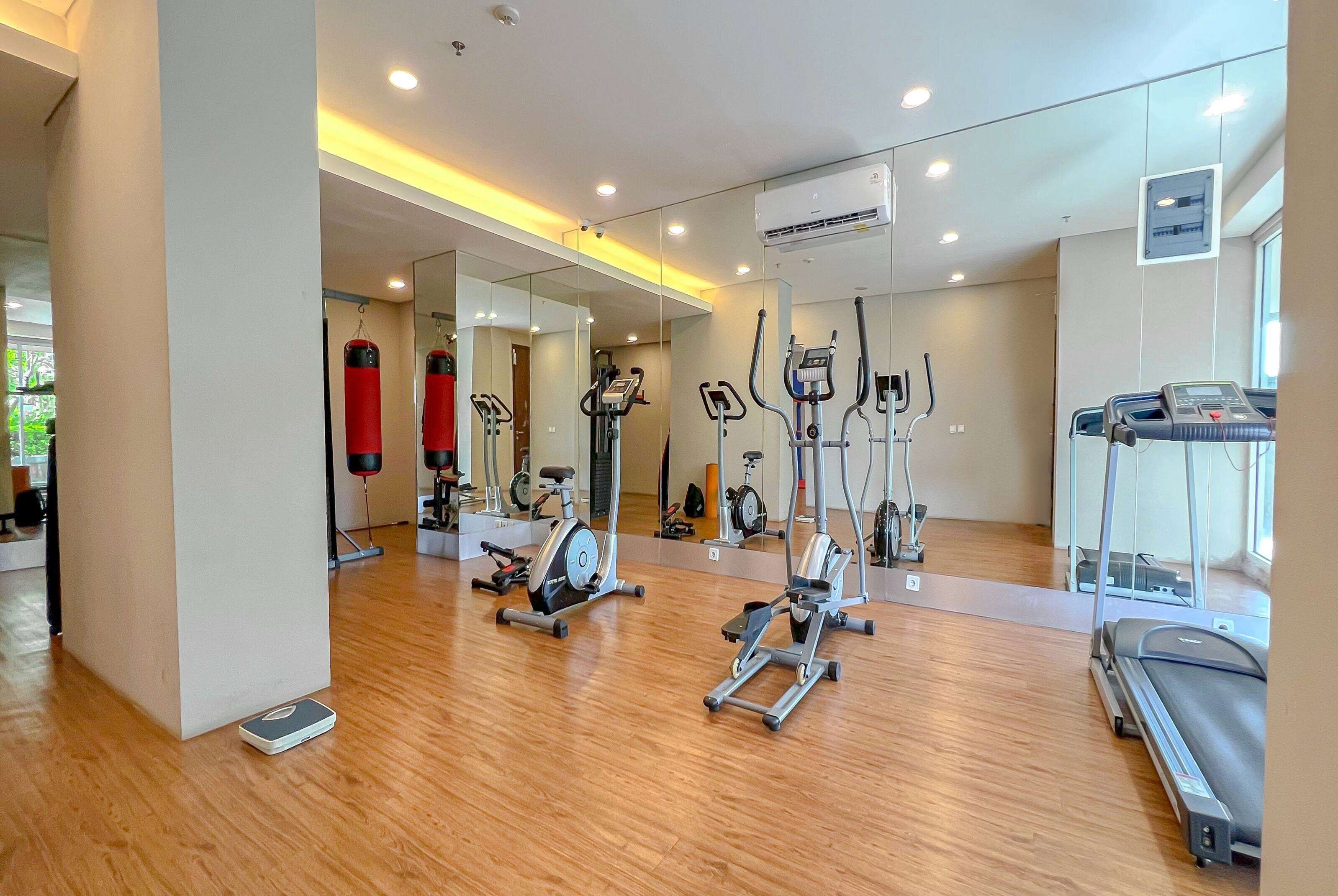A modern gym with various cardio machines, a large mirror, and a treadmill.