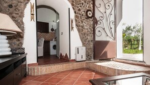 A spacious room with a stone wall, a washing machine, and a decorative metal piece. - B&B La Mimosa (Cava de' Tirreni)