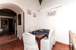 A dining area with a wooden table, white chairs, and a blue tablecloth. There are three wall-mounted paintings depicting floral arrangements. - B&B La Mimosa (Cava de' Tirreni)