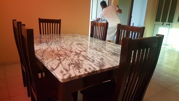 A dining area with a marble table and wooden chairs. - Casa Tchichi (São Filipe)