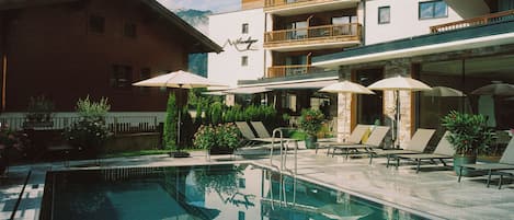 Una piscina cubierta, una piscina al aire libre, tumbonas