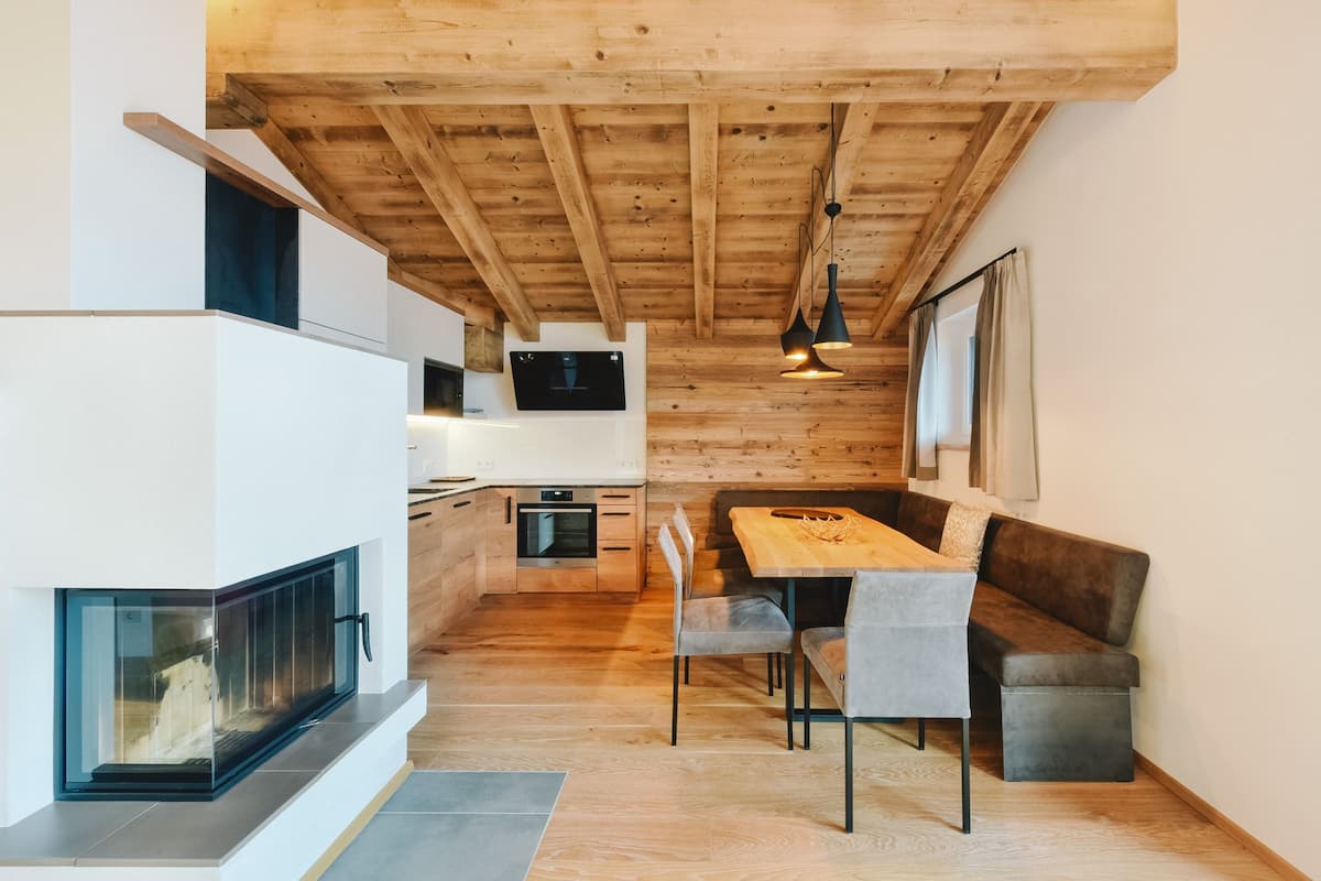 A modern kitchen with a built-in oven, a dining area with a wooden table and chairs, and a fireplace.