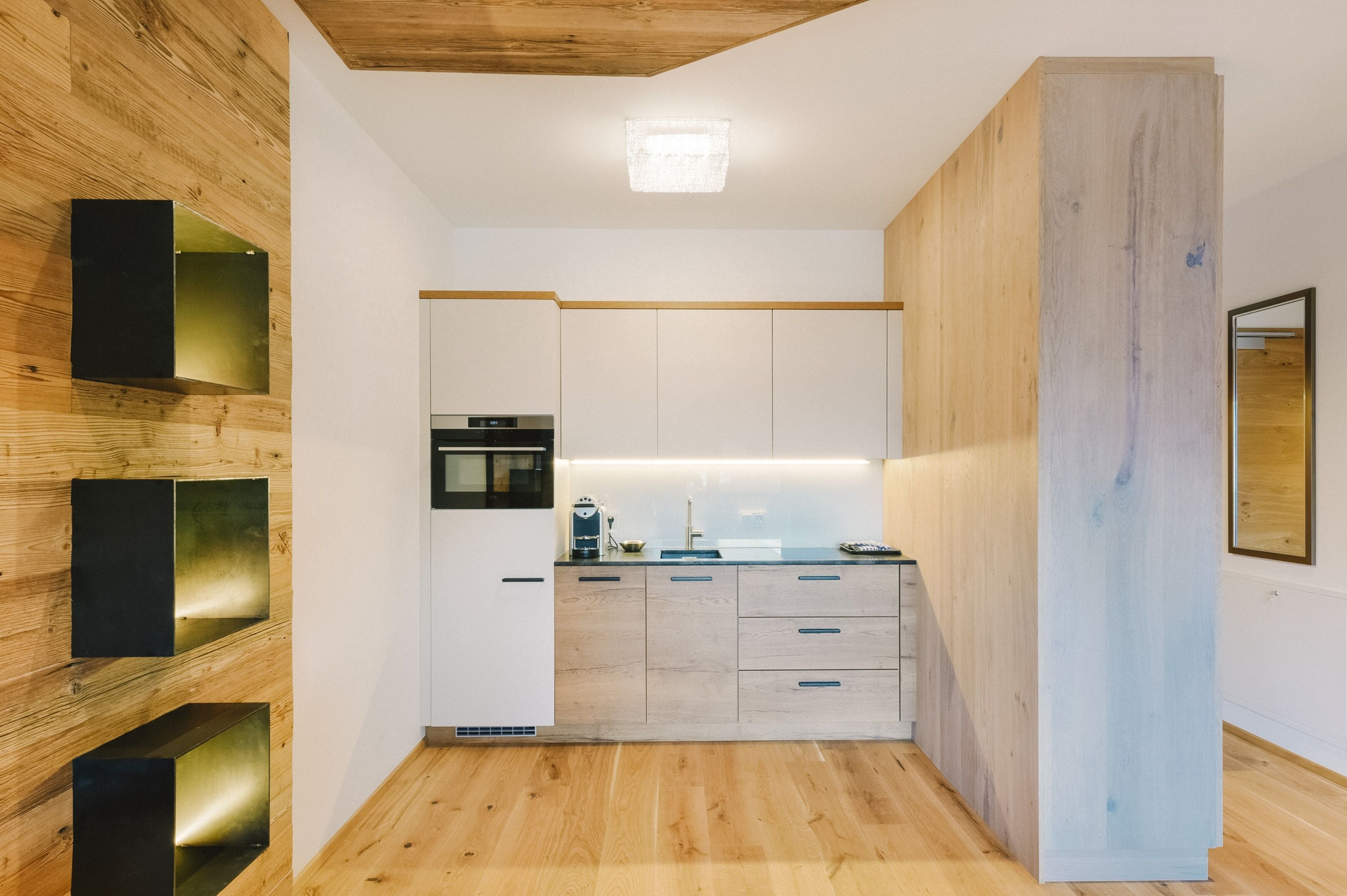 A modern kitchen with wooden cabinetry, a built-in oven, and a countertop with a coffee machine.