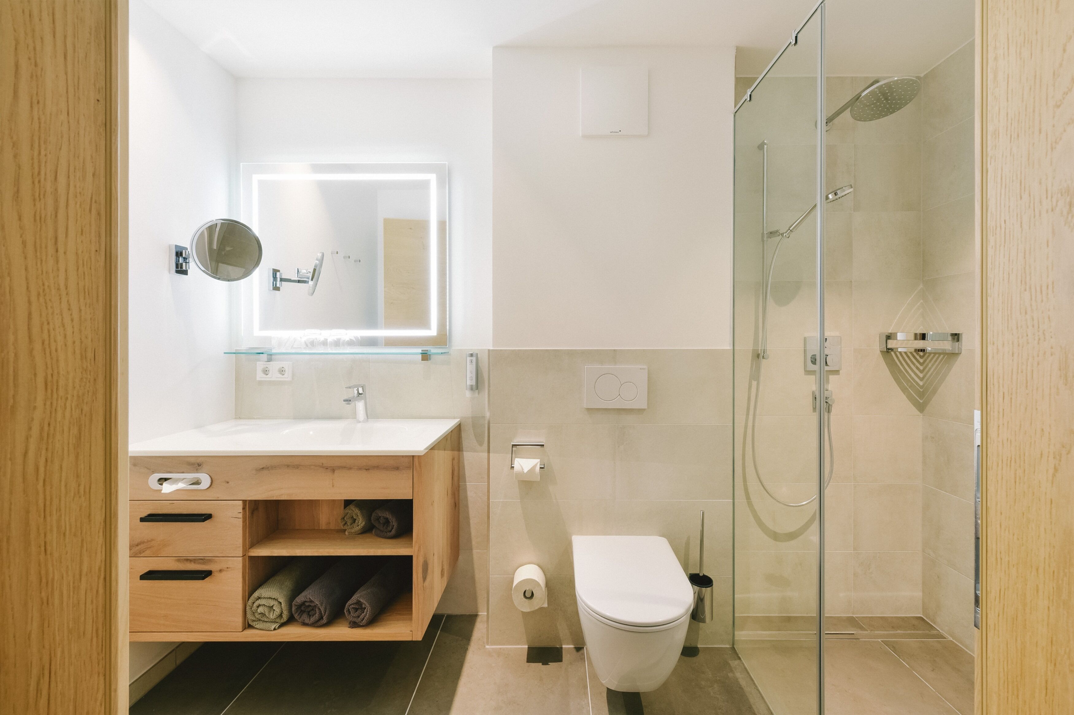 A modern bathroom with a glass shower enclosure, a wooden vanity with a mirror, and a toilet.