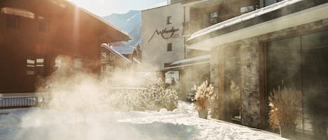 A hotel with a snow-covered exterior, a mountain backdrop, and a visible sign.