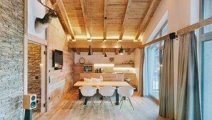 A modern kitchen with wooden beams, a stone wall, and a mounted deer head. - Venediger Lodge (Neukirchen am Grossvenediger)