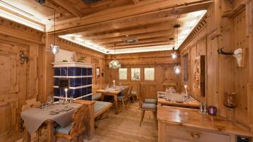 Un interior de madera con comedor, mesas dispuestas con vasos y cubiertos, y una pared decorativa con un cráneo.