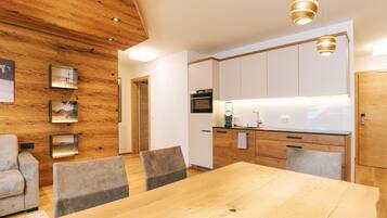 A modern kitchen with wooden cabinetry, a dining area with a wooden table and chairs, and pendant lighting.