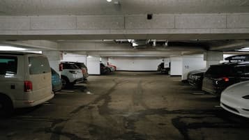 A multi-level underground parking garage with concrete walls and floors, featuring several parked cars and visible parking space numbers.