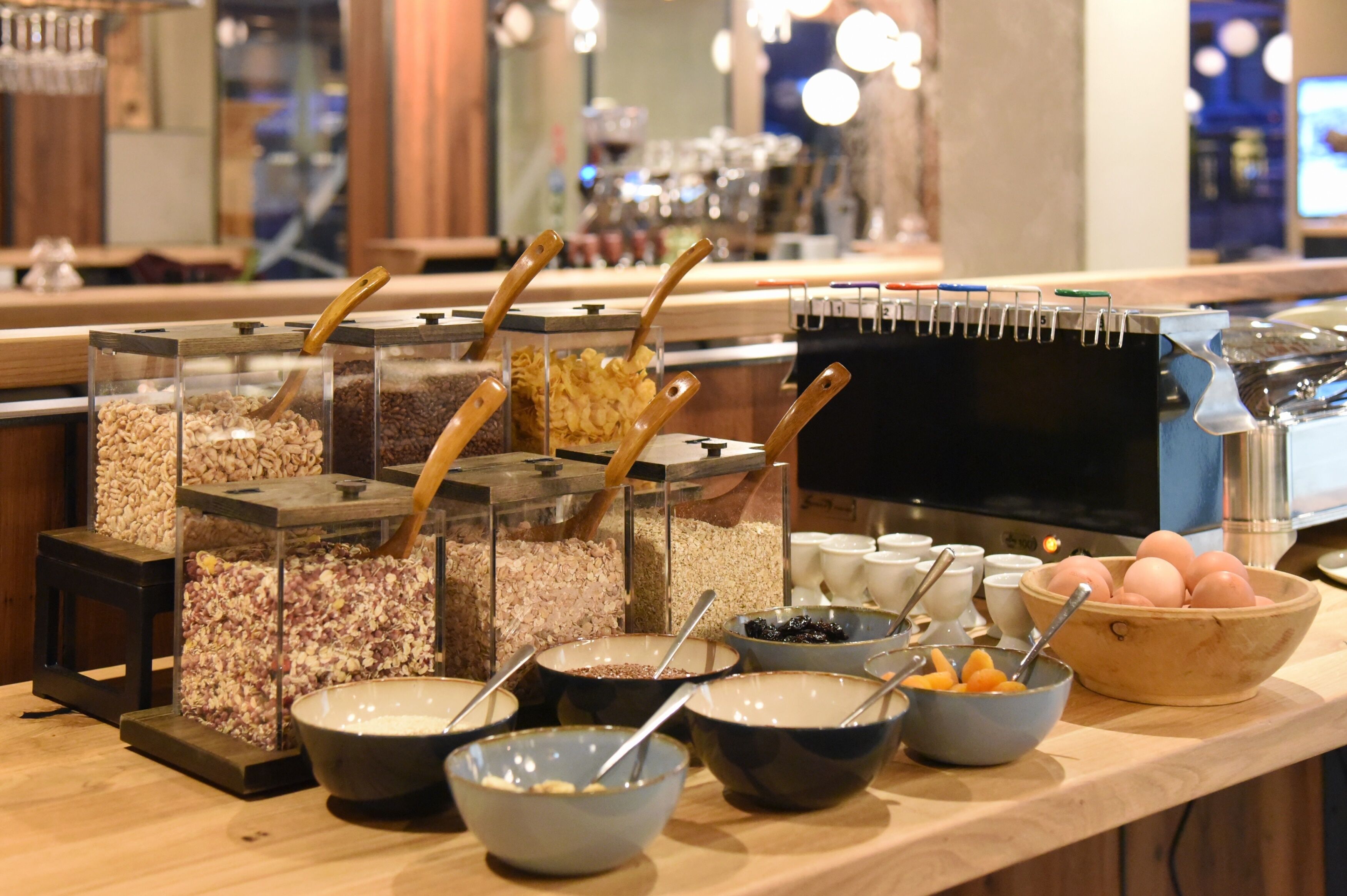 A buffet area with various food containers and bowls, including cereals, nuts, and fruits.