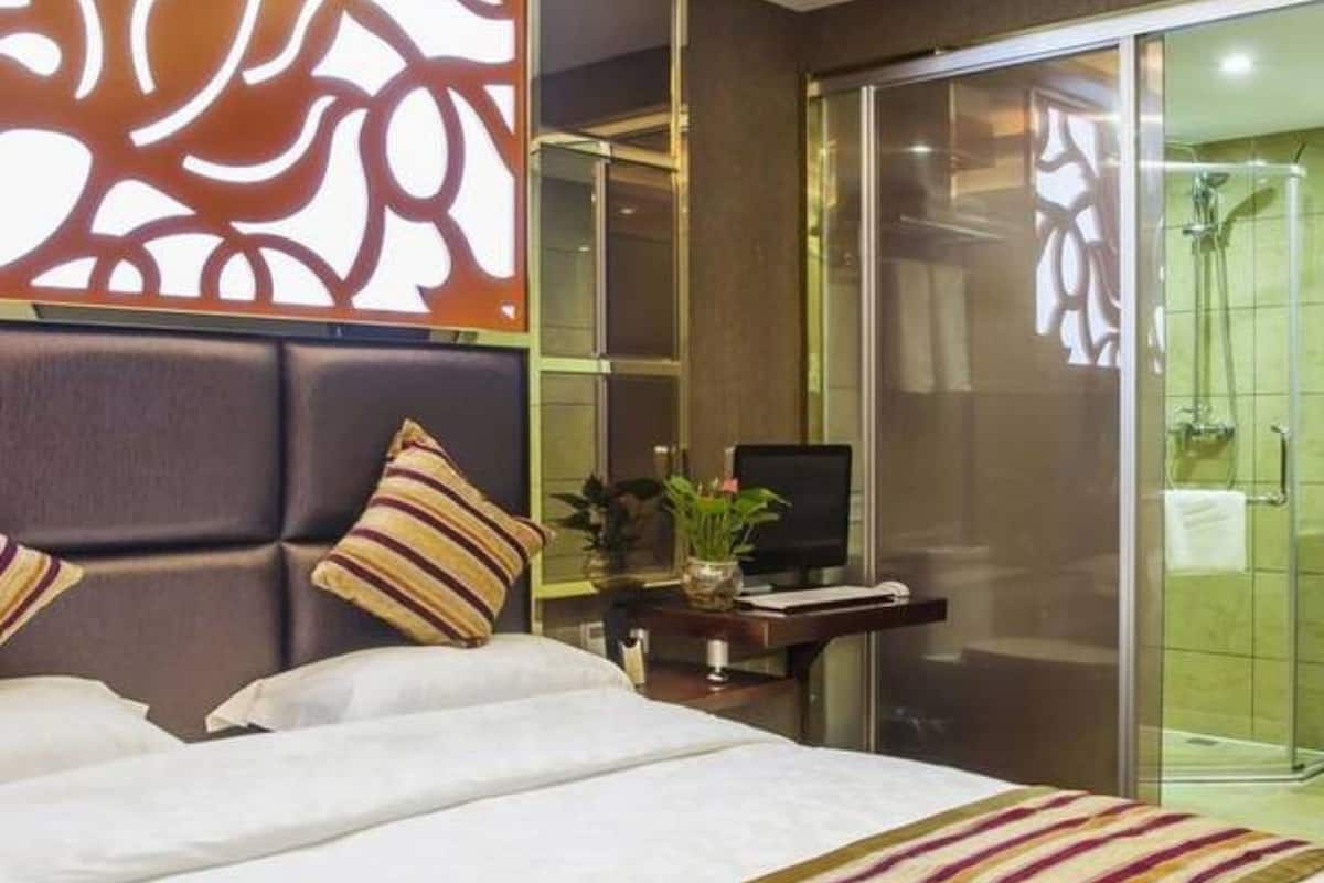 Hotellihuone, jossa on suuri sänky, televisio, työpöytä ja suihkutila.