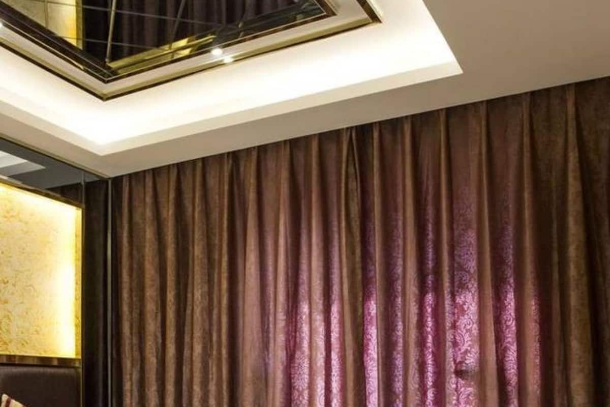 Hotellihuone, jossa on suuri sänky, kattovalokuvio ja kuvioitu matto.