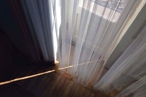 A room with a wooden floor and sheer curtains allowing natural light.