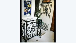 Eine Treppe mit aufwendigen schwarzen Metallgeländern, ein Gemälde mit blauen Rosen und eine kleine Pflanze.
