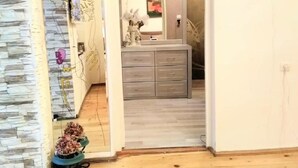 Ein Zimmer mit Steinwand, Holzboden, Schminktisch mit Spiegel und einer Blumenkomposition.