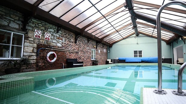 An indoor swimming pool with a glass ceiling, a brick wall, and a lifebuoy. - Faenol Fawr Hotel (Rhyl)
