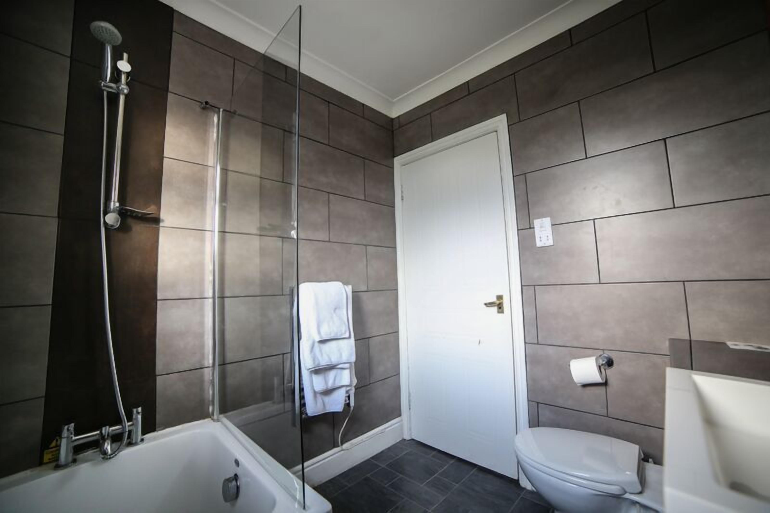 A bathroom with a shower, toilet, and a glass-enclosed shower area.
