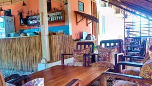 Een restaurant met een houten tafel en gestreept stoelen, een bar met flessen en een wand van bamboe.