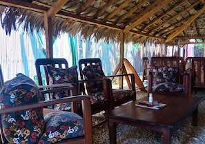 A covered outdoor seating area with wooden furniture and patterned cushions. - Hotel Le Petit Paradis (Antsiranana)
