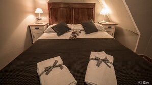 A neatly made bed with a wooden headboard, two bedside lamps, and a welcome home card on the pillows. - La Casa di Eio Traditional Apartment (Vernazza)