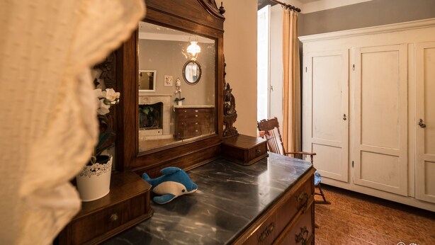 A room with a wooden dresser, a mirror, a small blue plush toy, a white door, and a white cabinet. - La Casa di Eio Traditional Apartment (Vernazza)