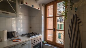 A kitchen with white cabinets, a stove, and a window with a view of buildings. - La Casa di Eio Traditional Apartment (Vernazza)