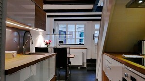 Eine kompakte Küche mit modernen Geräten, einem Essbereich und einem Fenster, das für natürliches Licht sorgt.