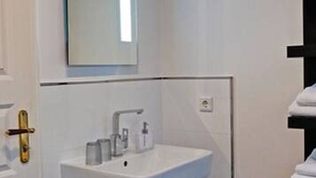 A modern bathroom with a white sink, mirror, and black tiled floor.