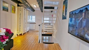 Ein modernes Interieur mit Holzboden, weißen Wänden und einer Treppe mit weißen Geländern.