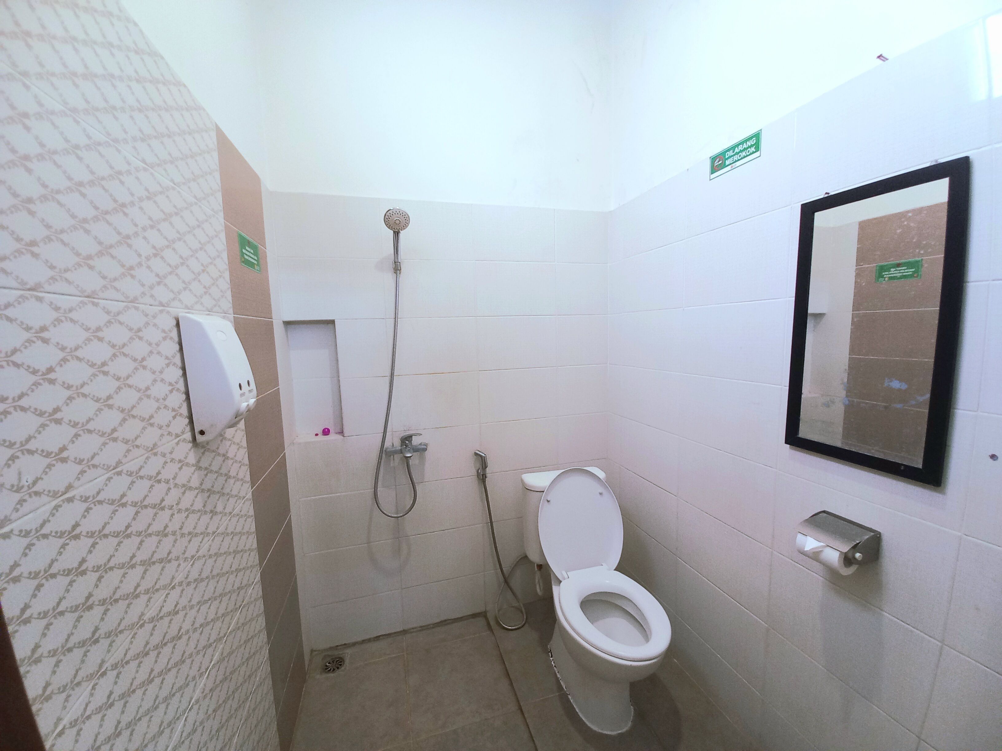 Un baño pequeño con azulejos, un inodoro, una ducha y un secamanos.