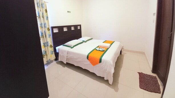 Een hotelkamer met een bed, een airconditioning, een deur en een klein vloerkleed.