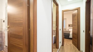 Un couloir avec des portes en bois donnant sur une chambre et une salle de bain.