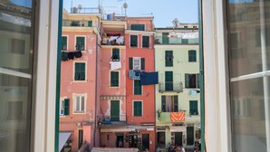 Une vue d’une rue étroite bordée de bâtiments aux couleurs vives, avec un café et des tables en terrasse.